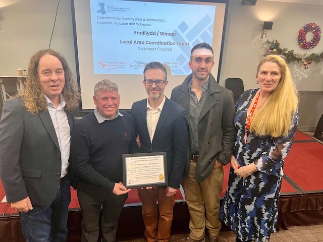 Photo of Jon Bevis, Dominic Nutt, Rónán Ruddy, Joseph Barry, and Natalie Ellis-Burt from the Swansea Local Area Coordination team, collecting their award.