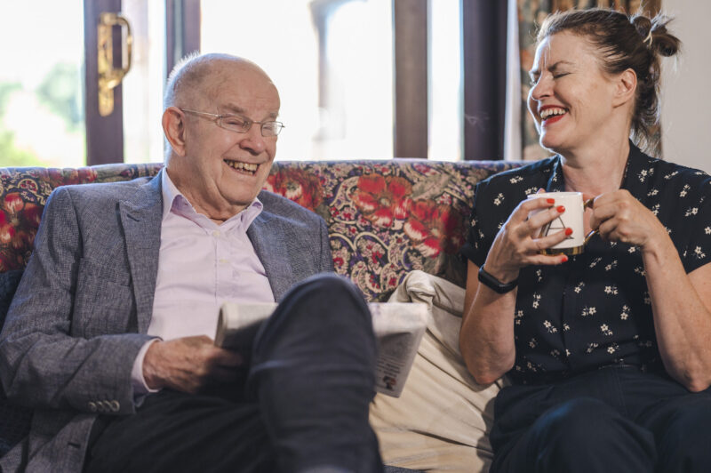 Man and woman sat laughing on sofa