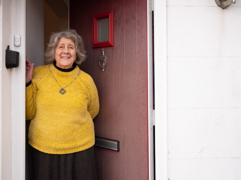 Elderly woman with yellow jump at the door smiling