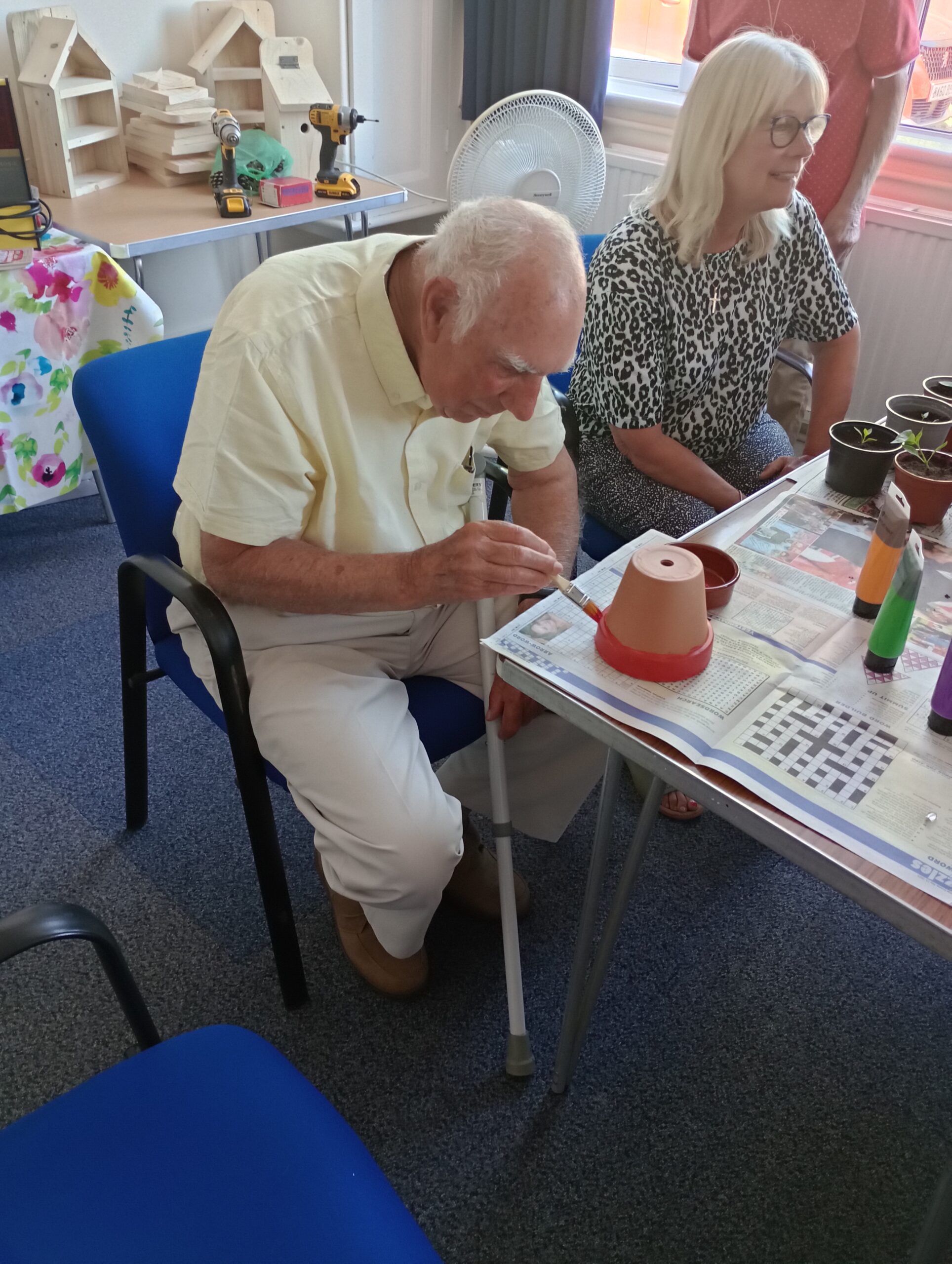 man painting a pot sat next to a woman