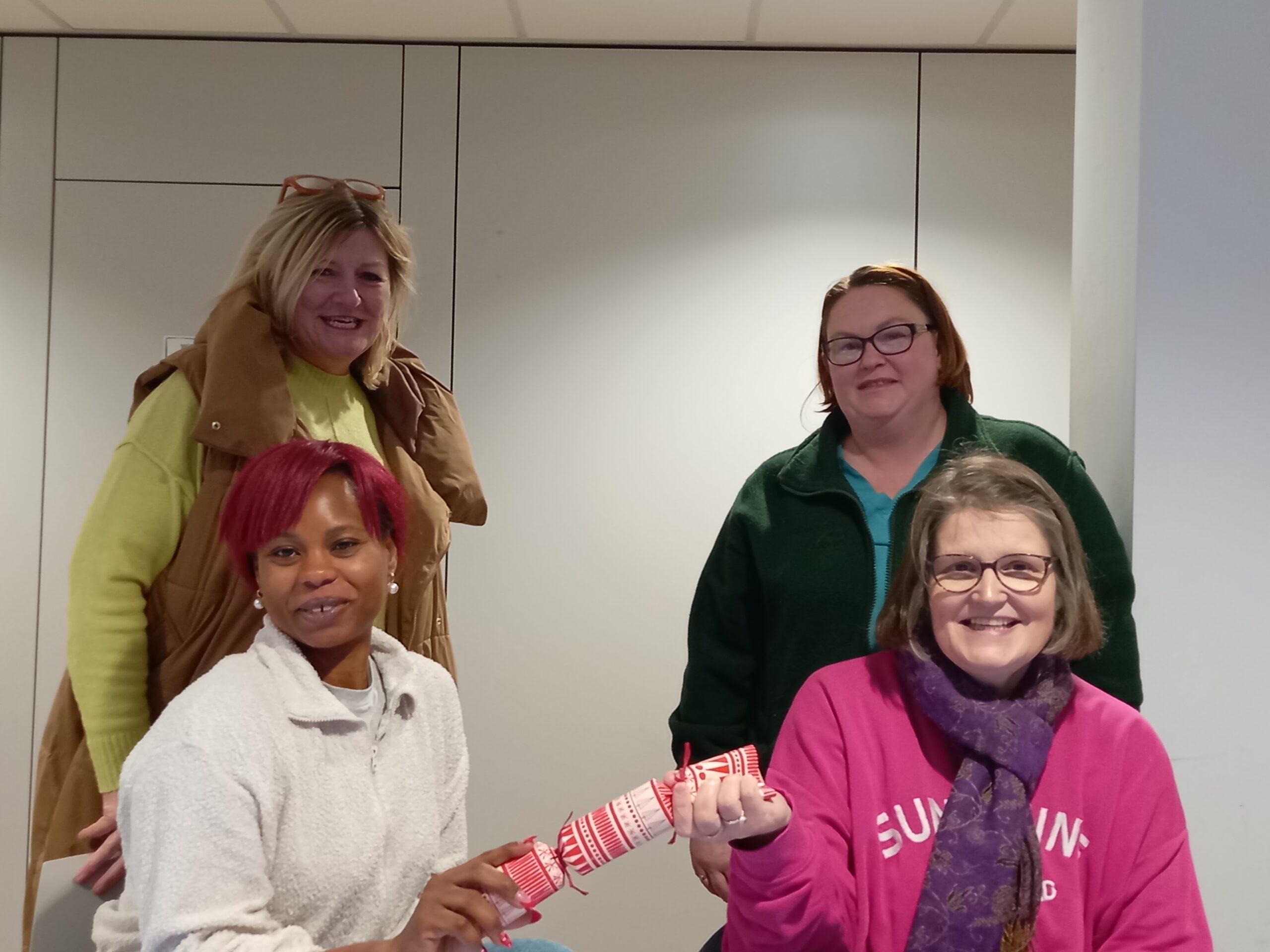 Women pulling Christmas cracker at Christmas get together