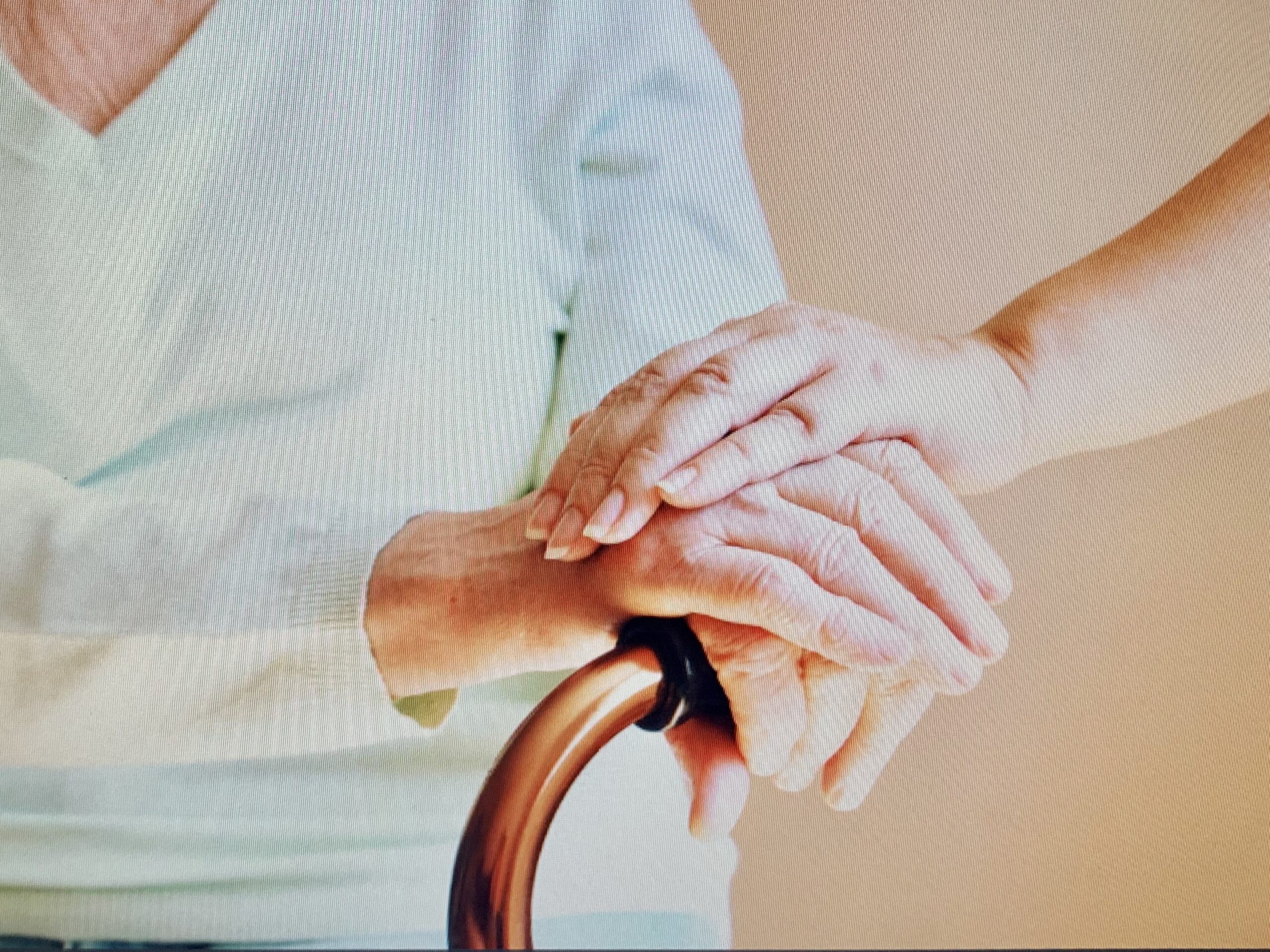 photo of two hands crossed over a walking stick