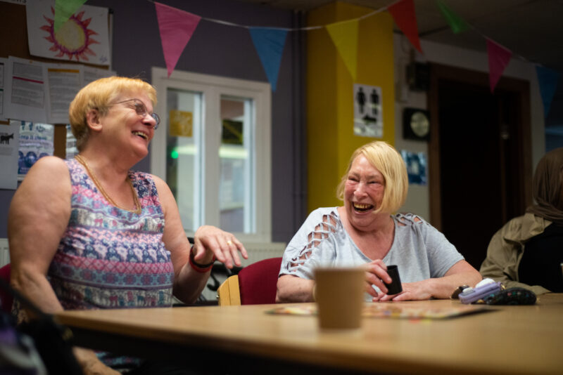 Two women sat at table laughing