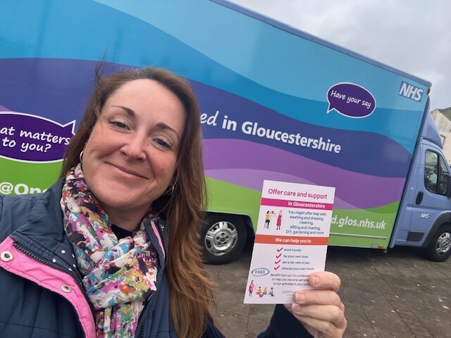 Photo of Heather with Comm Cats flyer in front of information bus