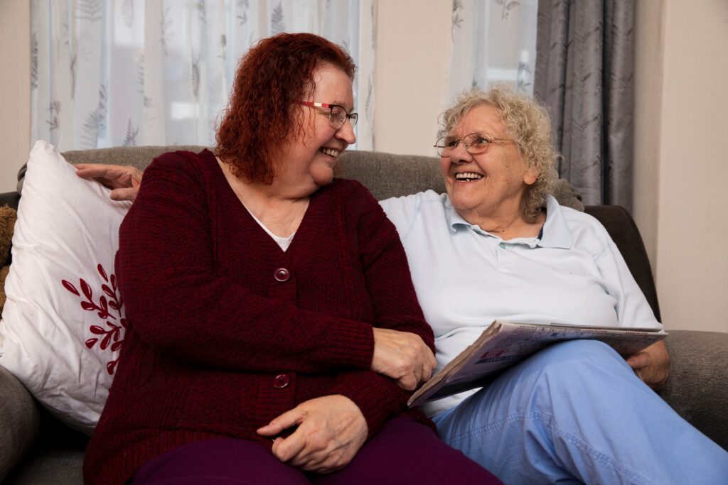 Two women sitting together on a couch.