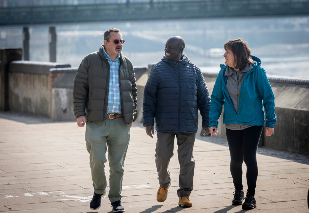 Three people walking by river