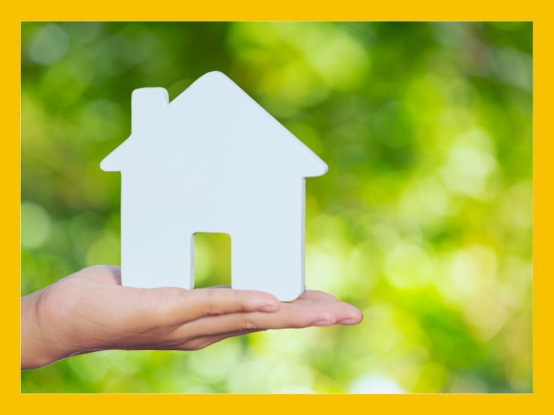 A hand holding a white cardboard house