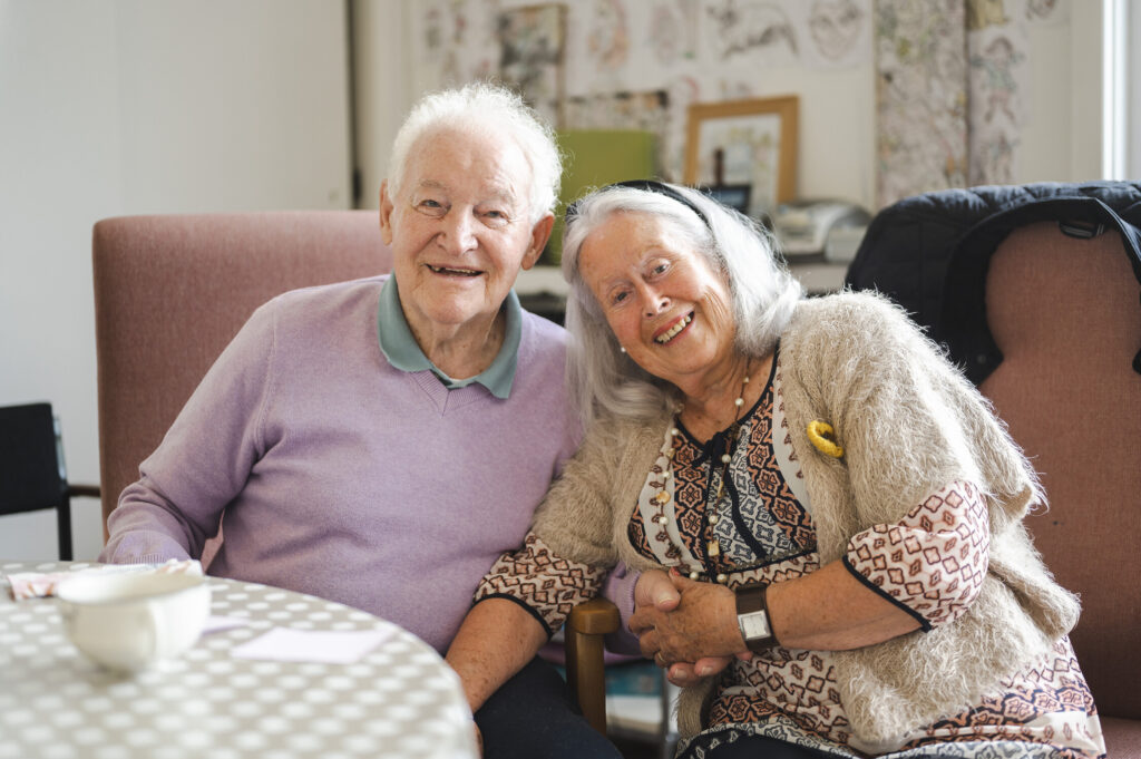 An older man and woman sitting together and smiling at camera