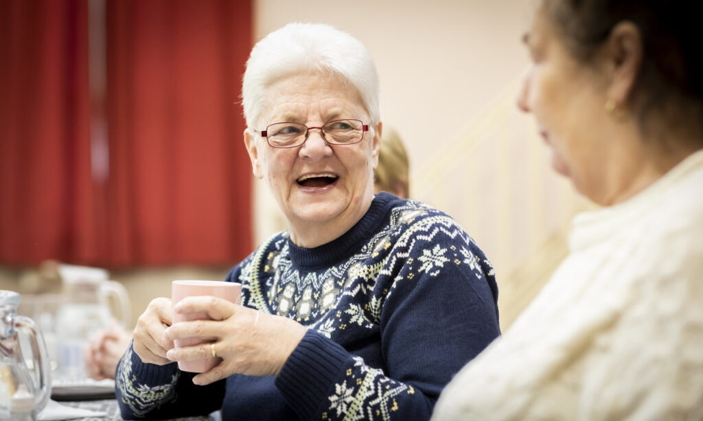 Woman smiling at another woman.