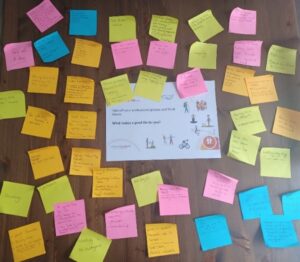 Lots of coloured post it notes arranged around a poster that says 'take off your professional glasses and think about what makes a good life for you'