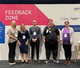 Members of the Community Catalysts and Employment is for Everyone team stood in front of a feedback wall at the NCASC event