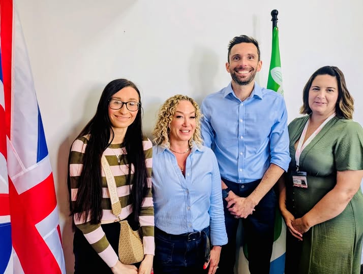 Four people standing in a room, smiling at the camera.