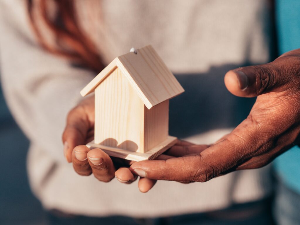 Hands holding a small timber house