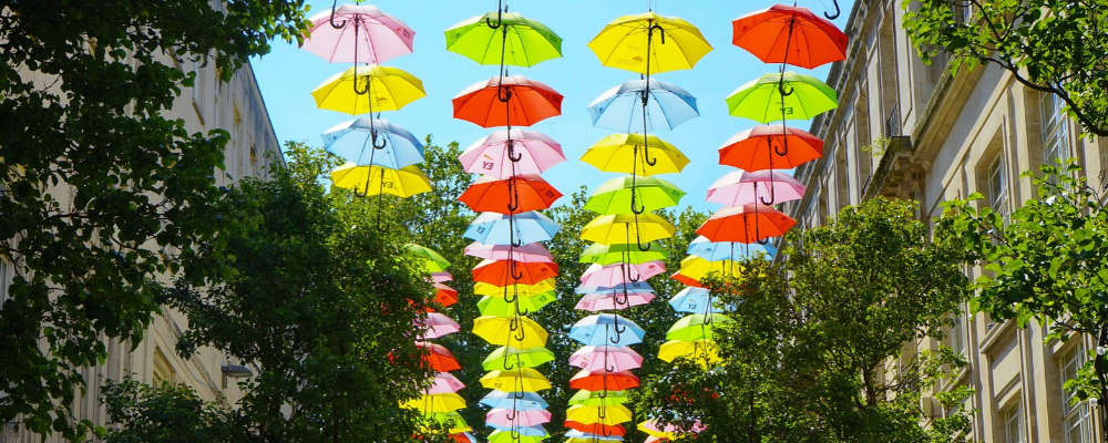 Rows of umbrellas in bright colours hanging across a street